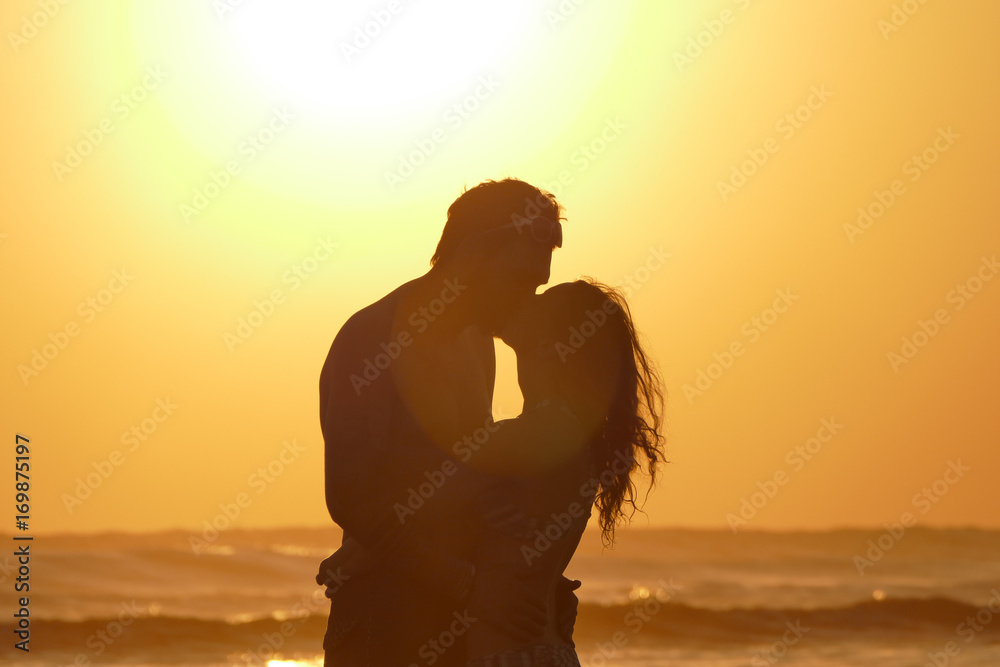 Fototapeta premium Aoung couple is kissing at beach during sunset