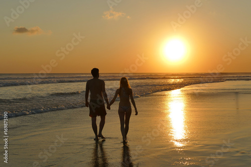 Young couple walking on beach during sunset