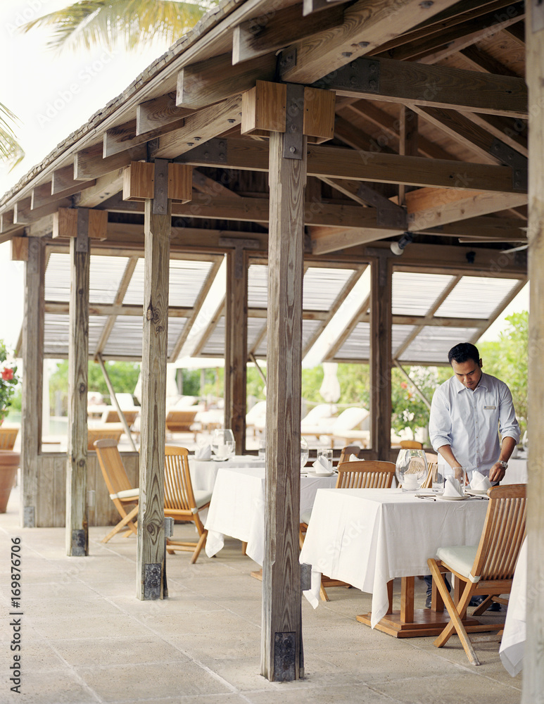 Waiter setting tables for lunch in restaurant Waiter setting tables for lunch in restaurant