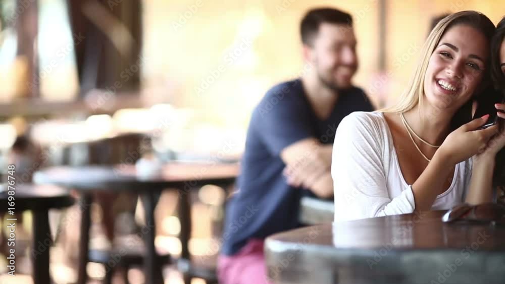 To female friends talk on a mobile phone simultaneously in a cafe shop. To female friends talk on a mobile phone simultaneously in a cafe shop.