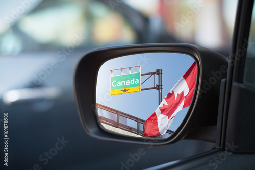 Left side car mirror showing Canadian flag, departure concept