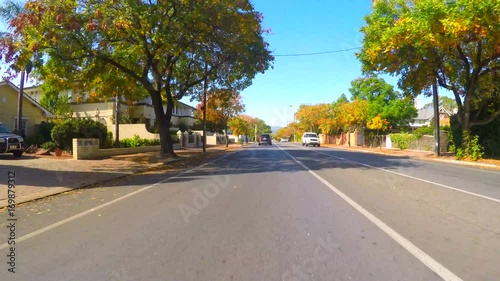 4k Vehicle POV, driving along suburban street on a sunny day in early Autumn. photo