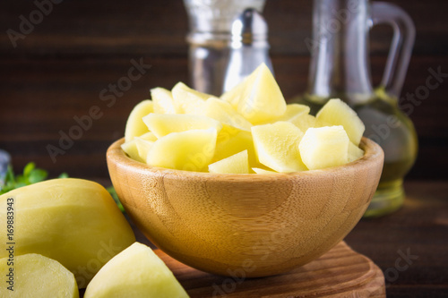 Raw peeled and sliced potatoes on an old weathered wooden table