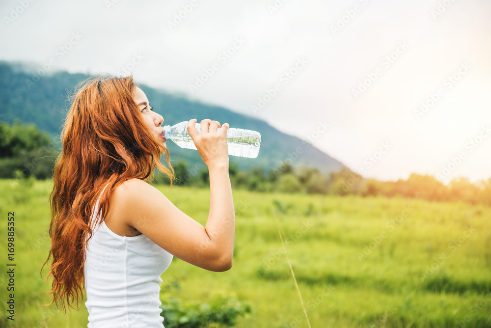 Asian women travel relax in the holiday. Drink Water on a green pasture. Asian women travel relax in the holiday. Drink Water on a green pasture.