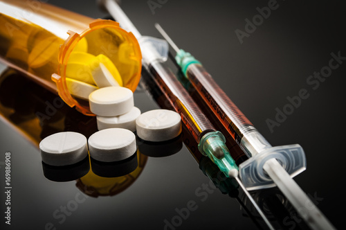 Opioid epidemic, drug abuse concept with closeup on two heroin syringes or other narcotics surrounded by scattered prescription opioids. Oxycodone is the generic name for a range of opioid painkillers photo