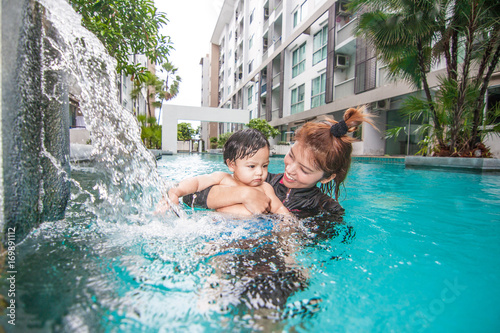 The kid and mom play together in the pool
