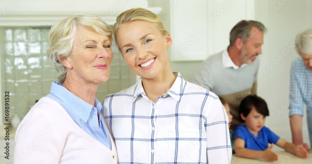 Smiling senior woman and daughter standing with arm around at home Smiling senior woman and daughter standing with arm around at home