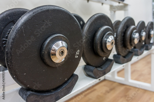 Many weight sizes of barbell plates in a gym. They are fitness equipments.