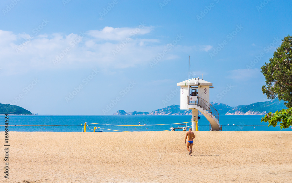 Obraz premium Tourist and enclosed lifeguard patrol tower on beach. They are at Repulse Bay in Hong Kong.