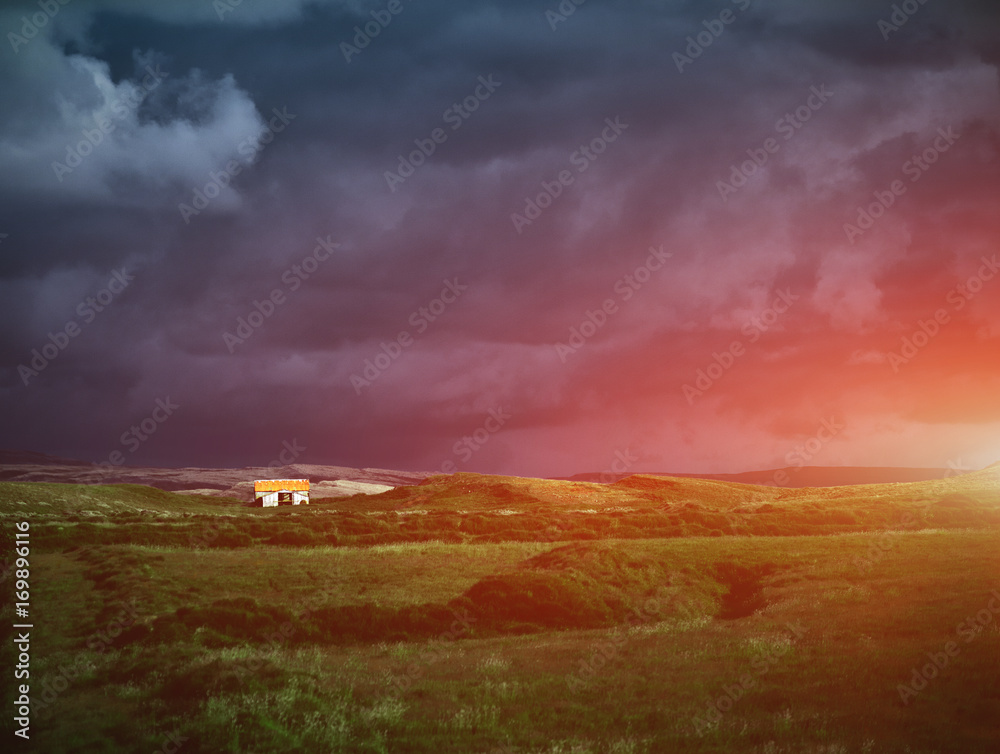 Travel to Iceland. The charming rustic rural house on dark cloudy sky background