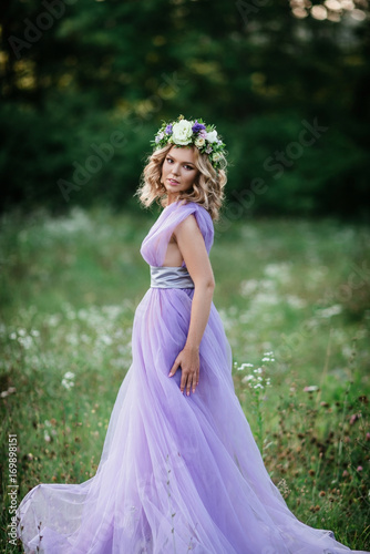 beauty woman portrait with wreath of flowers on head. bride in purple dress Outdoor. soft focus