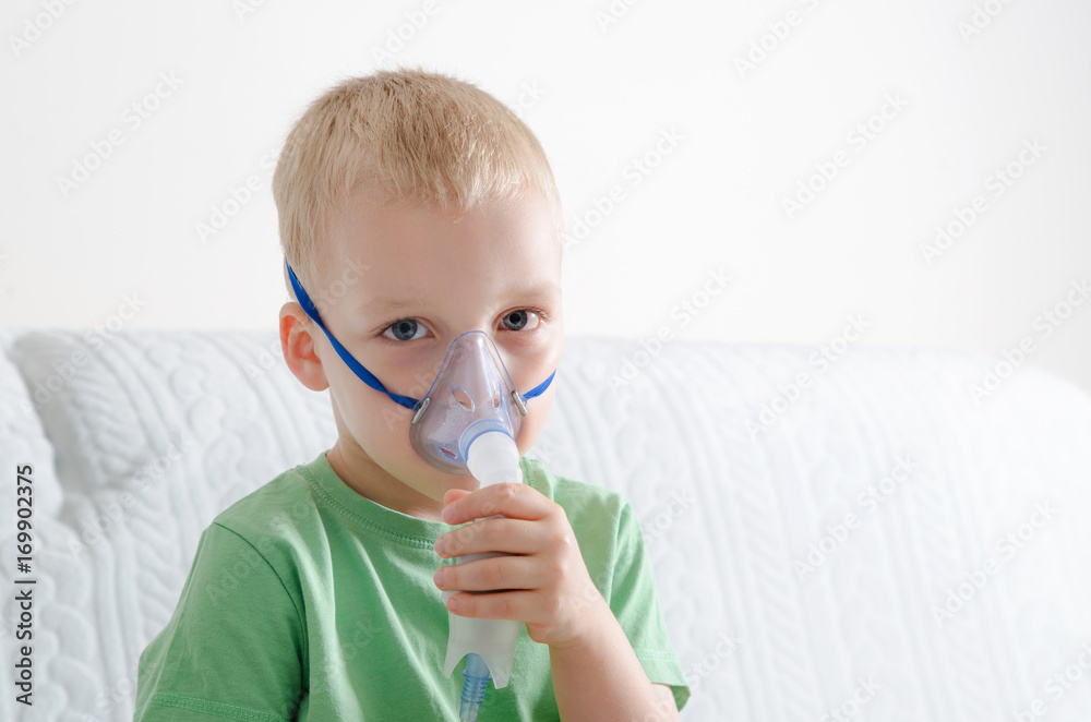 Boy making inhalation with nebulizer at home