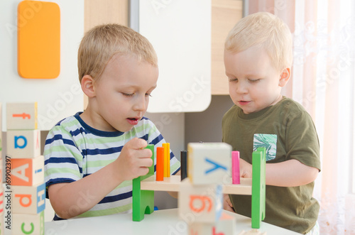 Kids boys playing with toy blocks at home or kindergarten