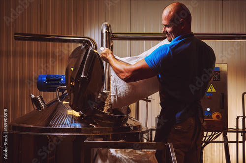 Brewer in brewhouse pouring out the malt to the tank