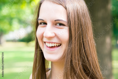 Portrait young smiling woman with long hair in summer park