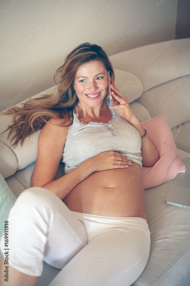 Naklejka premium Caucasian pregnant woman talking on the smart phone.