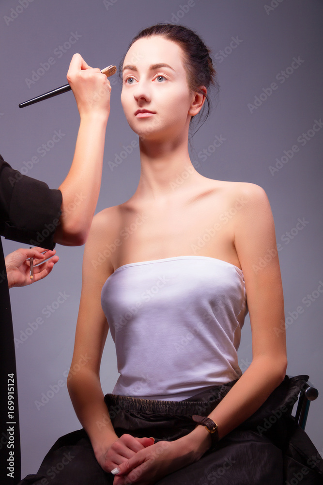 Obraz premium Female / woman / girl preparing for show. Makeup artist with makeup brush for eye doing professional makeup for young woman. Backstage