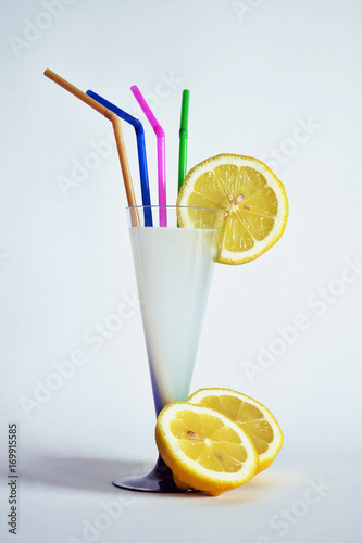 bere una limonata una limonata dentro ad un bicchiere a forma di calice, a lato un limone tagliato in due parti photo