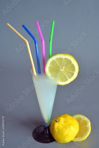 bere una limonata una limonata dentro ad un bicchiere a forma di calice, a lato un limone tagliato in due parti photo