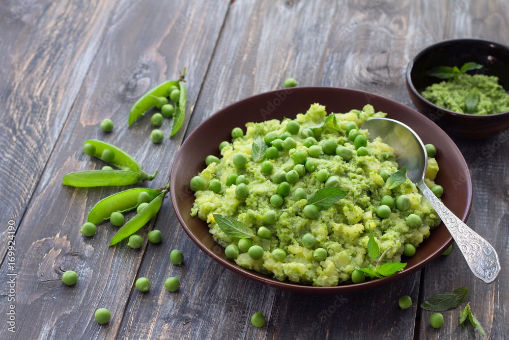 Mashed potatoes with green peas, mint and olive oil in a ceramic bowl on a wooden table. Healthy vegetarian food Mashed potatoes with green peas, mint and olive oil in a ceramic bowl on a wooden table. Healthy vegetarian food