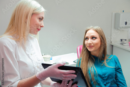 female dentist with patient girl talking at dental clinic office