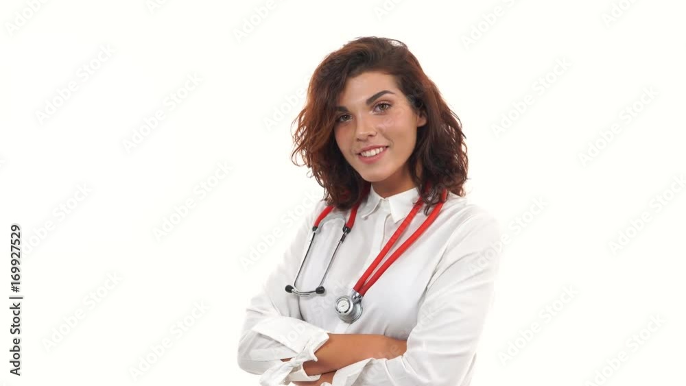 Young female doctor walking in and smiling warmly and looking at camera. Portrait of young medical professional with stethoscope and lab coat isolated on white background. 4k shot Young female doctor walking in and smiling warmly and looking at camera. Portrait of young medical professional with stethoscope and lab coat isolated on white background. 4k shot