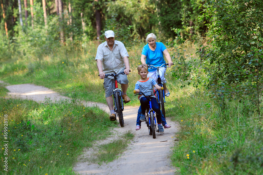 active senior couple with kids riding bikes in nature active senior couple with kids riding bikes in nature