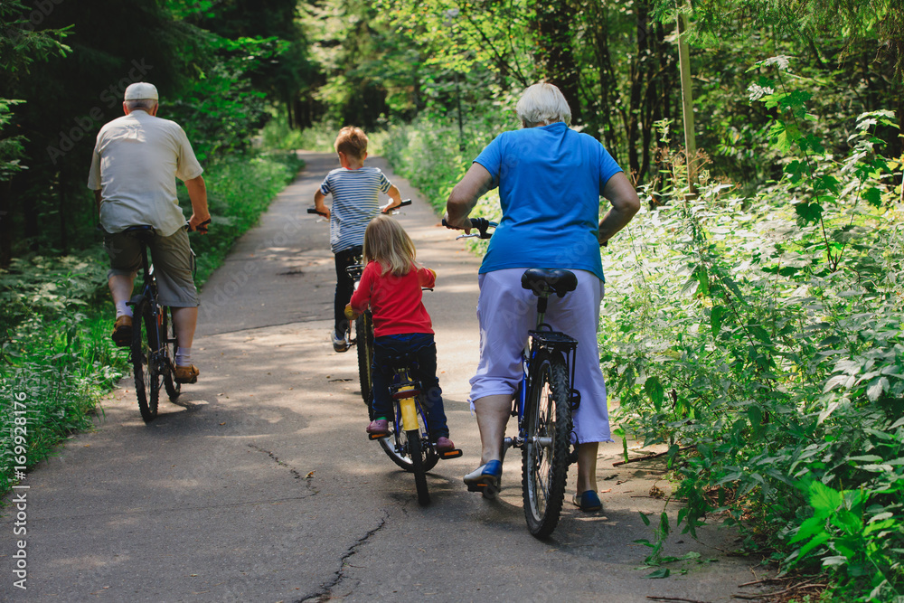 Obraz premium active senior couple with kids riding bikes in nature