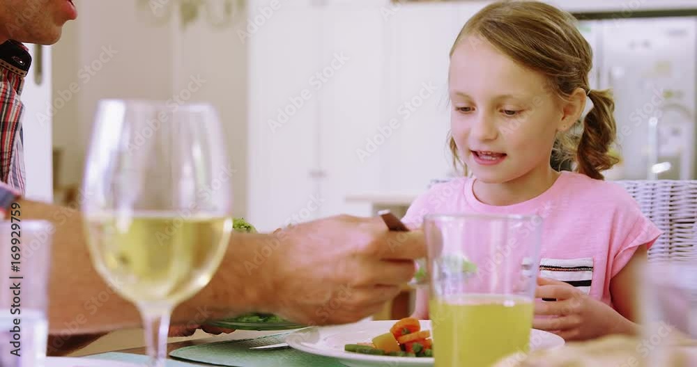 Father serving salad to daughter on dining table Father serving salad to daughter on dining table