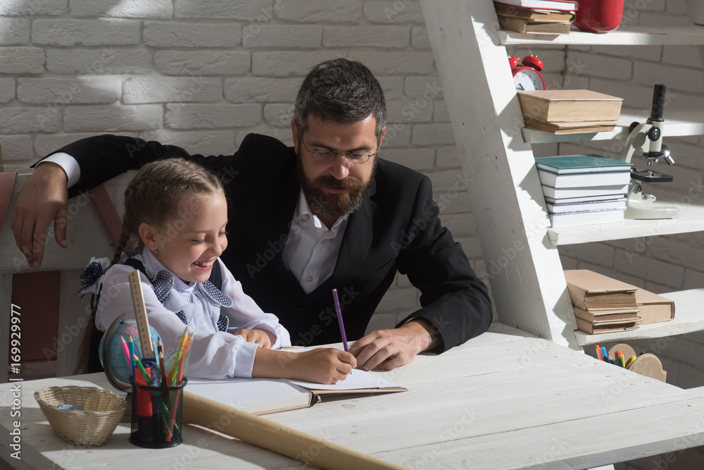 Kid and man sit by desk with school supplies Kid and man sit by desk with school supplies