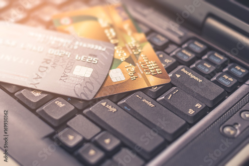 The abstract image of credit cards on the laptop keyboard during sunshine. the concept of online shopping, online payment, e-commerce, cybersecurity and internet of things.