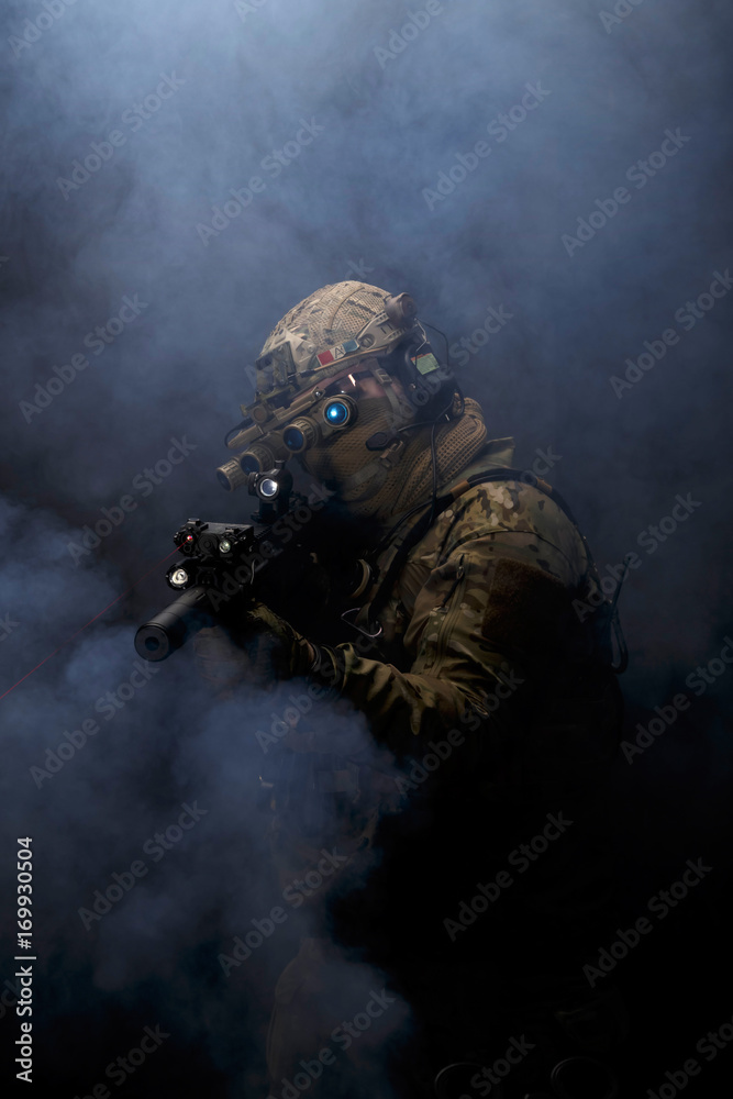 Soldier in military uniform with assault rifle aiming with laser at target in smoke on background of dark wall 15 Soldier in military uniform with assault rifle aiming with laser at target in smoke on background of dark wall 15
