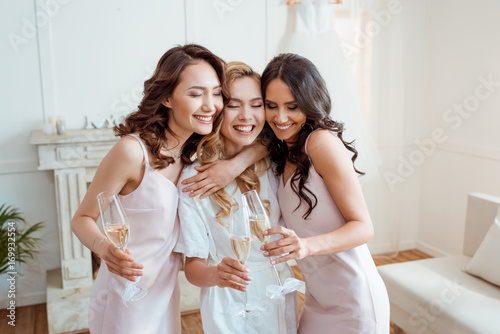 bride with bridesmaids embracing and toasting photo