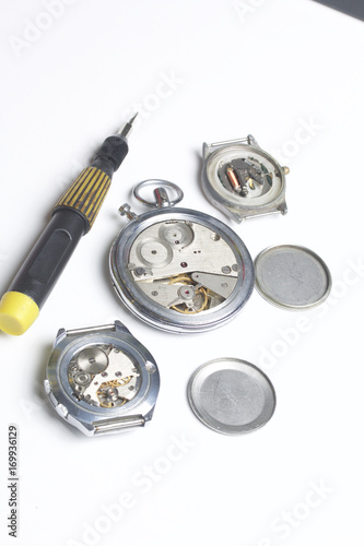 The watch workshop. Repair of old watches. The mechanism of the clock, the screwdriver, which the master makes repairs, is visible. On a white background. photo