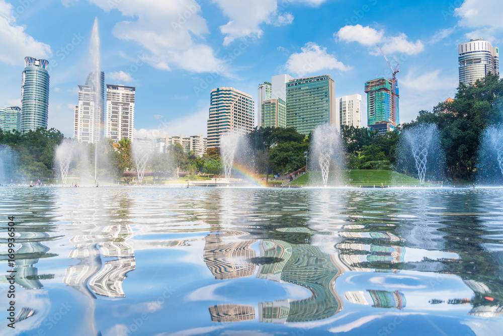 Kuala Lumpur skyscraper reflection with rainbow in blue sky, Malaysia.