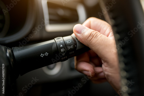 Car interior, hand on car headlight switch