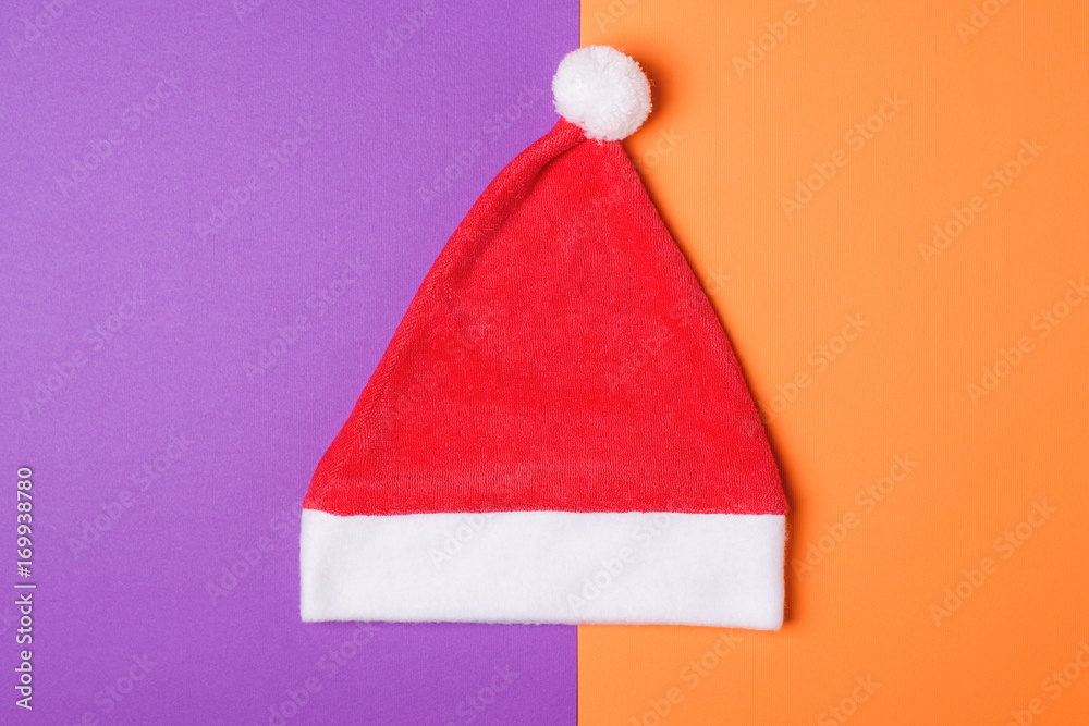 Santa Claus red hat on orange and wiolet paper background , minimal style. Santa Claus red hat on orange and wiolet paper background , minimal style.