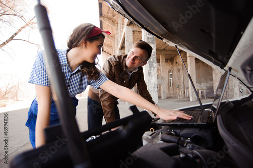 Professional auto woman mechanic and man repair auto outdoors