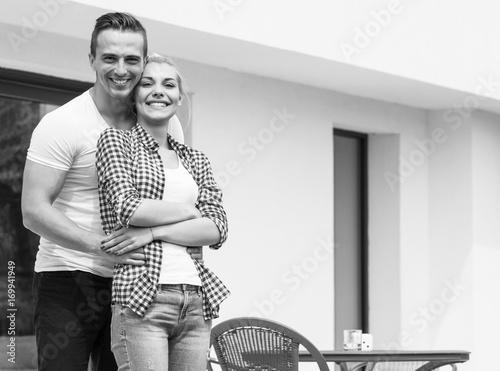 Happy two young lovers standing in front of modern house photo