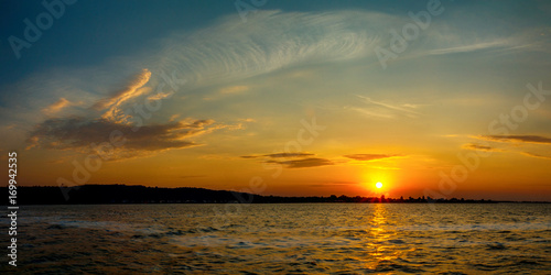 Stunning sunset colors with the cloudy skyin the river in a summer evening. Dramatic clouds. photo