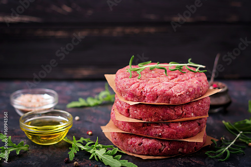 Fresh raw homemade minced beef steak burger with spices on black background