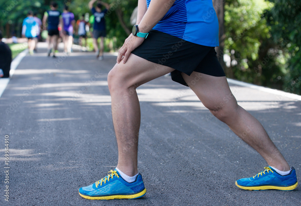 Attractive young man stretching on the track before running