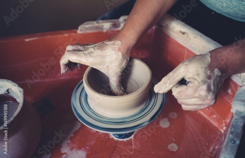 Photo Work in a pottery workshop, womans hands creating ceramics.