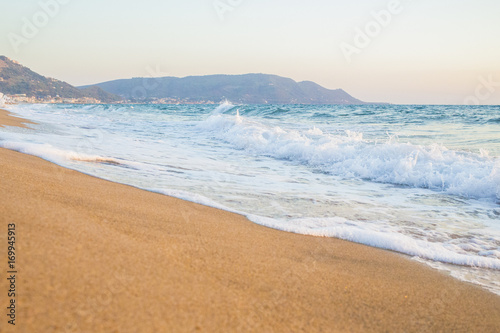 Tratto di costa con spiaggia e mare vicino Santa Maria di Castellabate. L'acqua è pulita ma mossa e ci sono molte onde. La spiaggia è tra l'arancione e il giallo e rispecchia i colori del tramonto photo