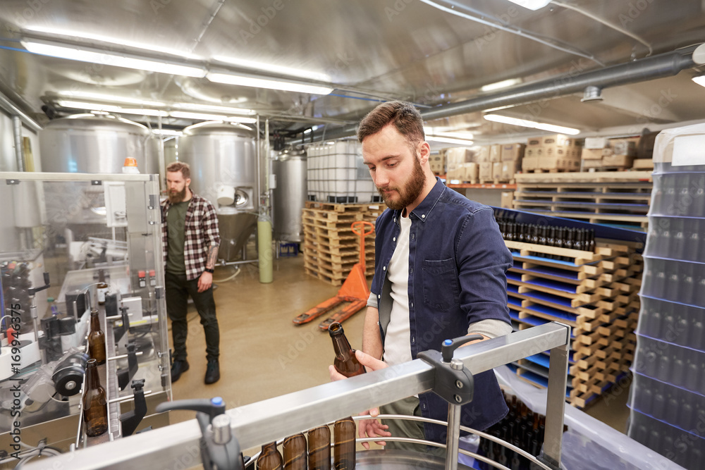 men with bottles on conveyor at craft beer brewery