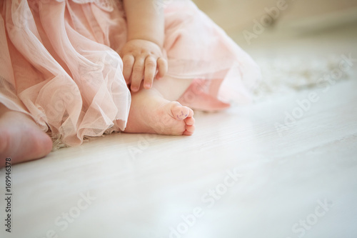 little baby on the floor with drawn smiley face on her big toe