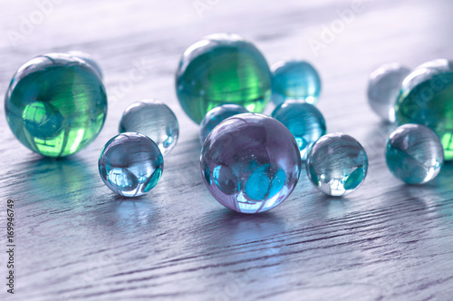 Glass balls of blue and green on a wooden surface.