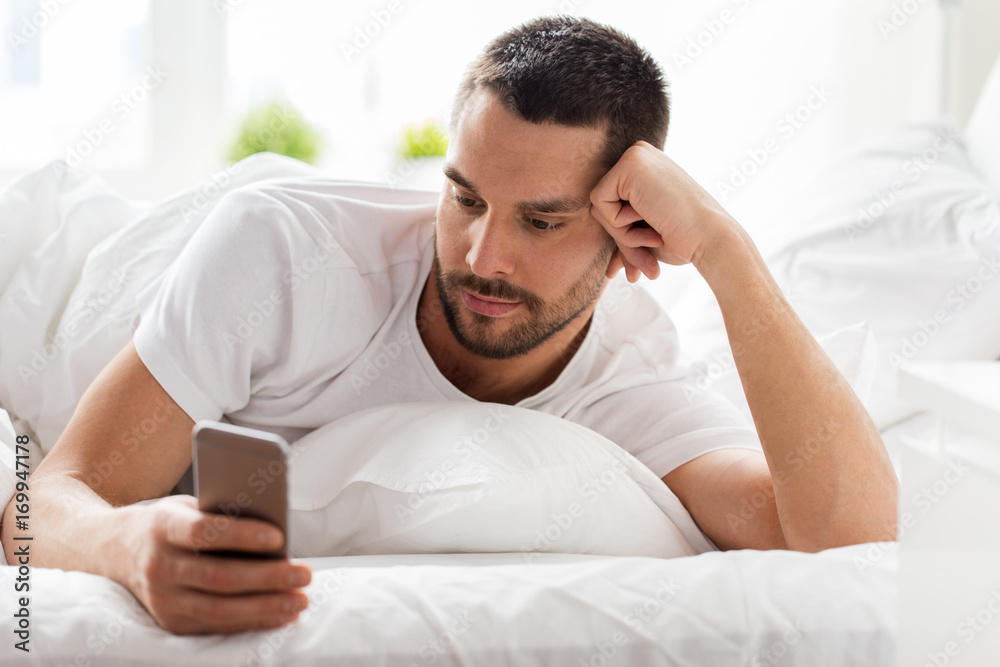 young man with smartphone in bed in morning young man with smartphone in bed in morning