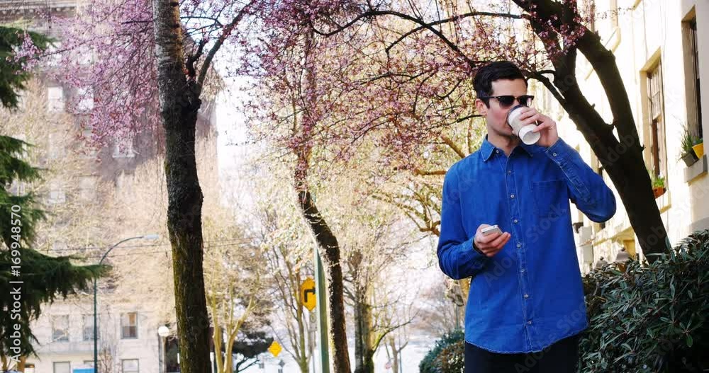 Man using mobile phone while having coffee in park Man using mobile phone while having coffee in park