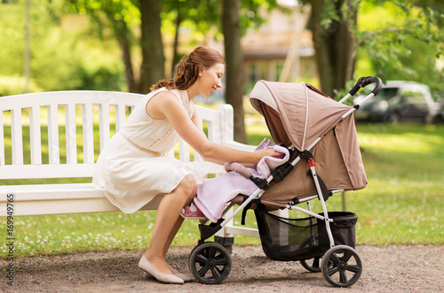 Obraz na plátně happy mother with child in stroller at summer park